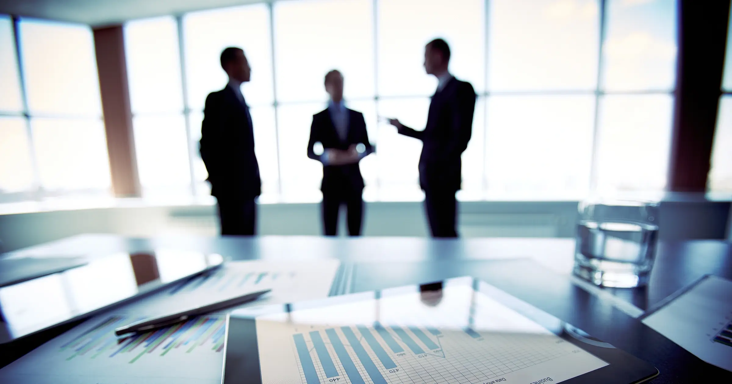 A tablet on a desk in front of a group of business people