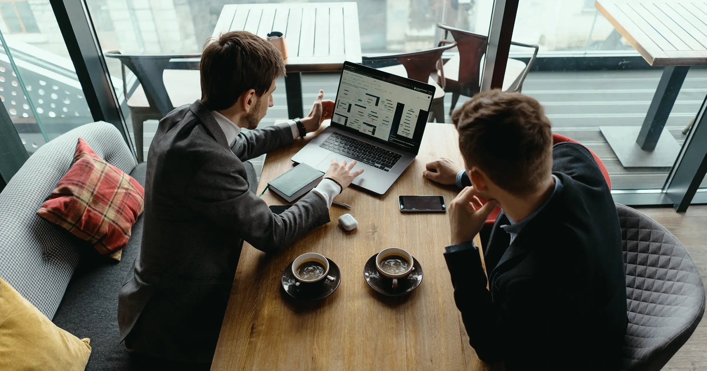 Two men discussing a project over coffee