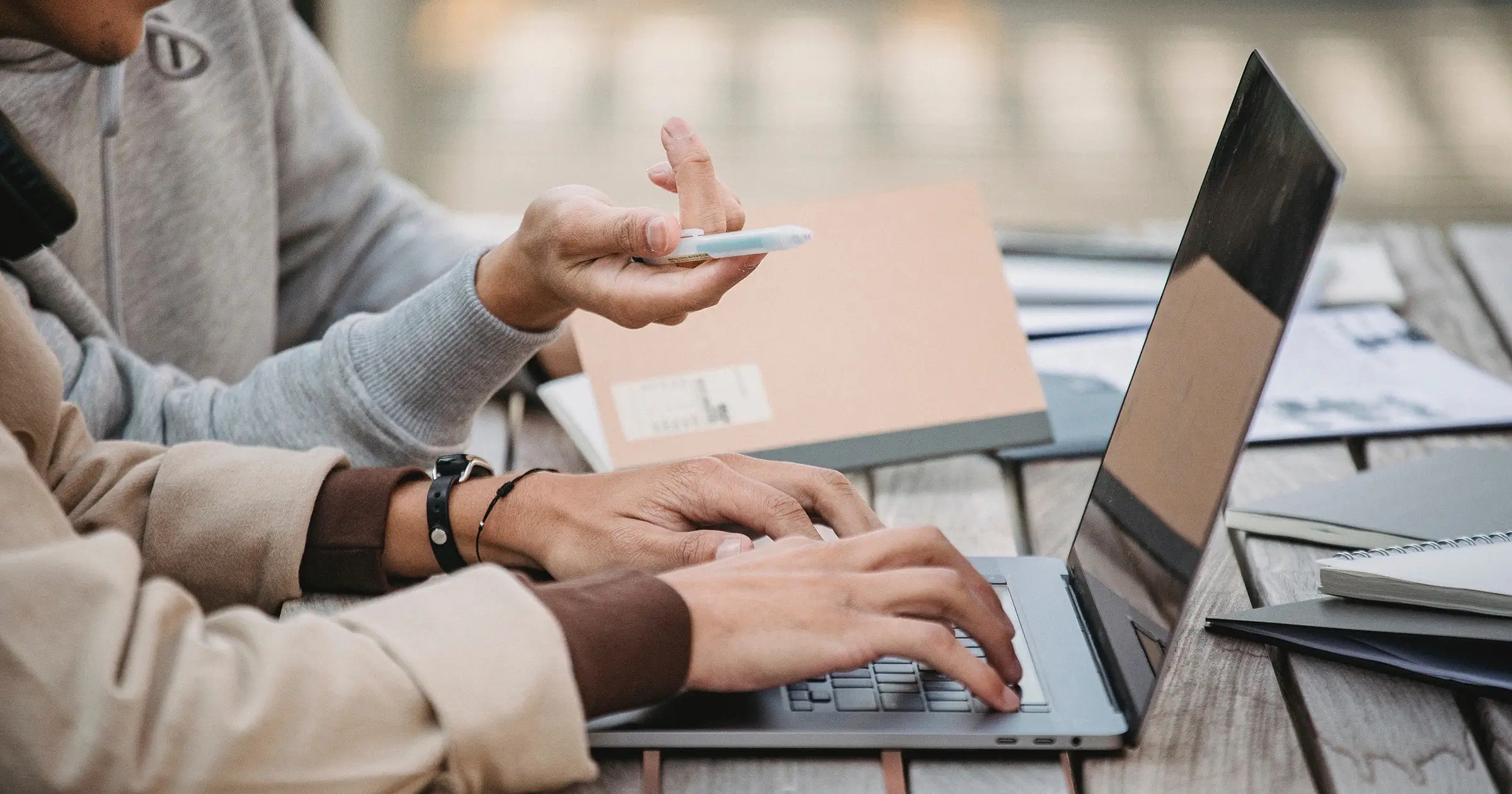 Two people pointing and typing on a laptop