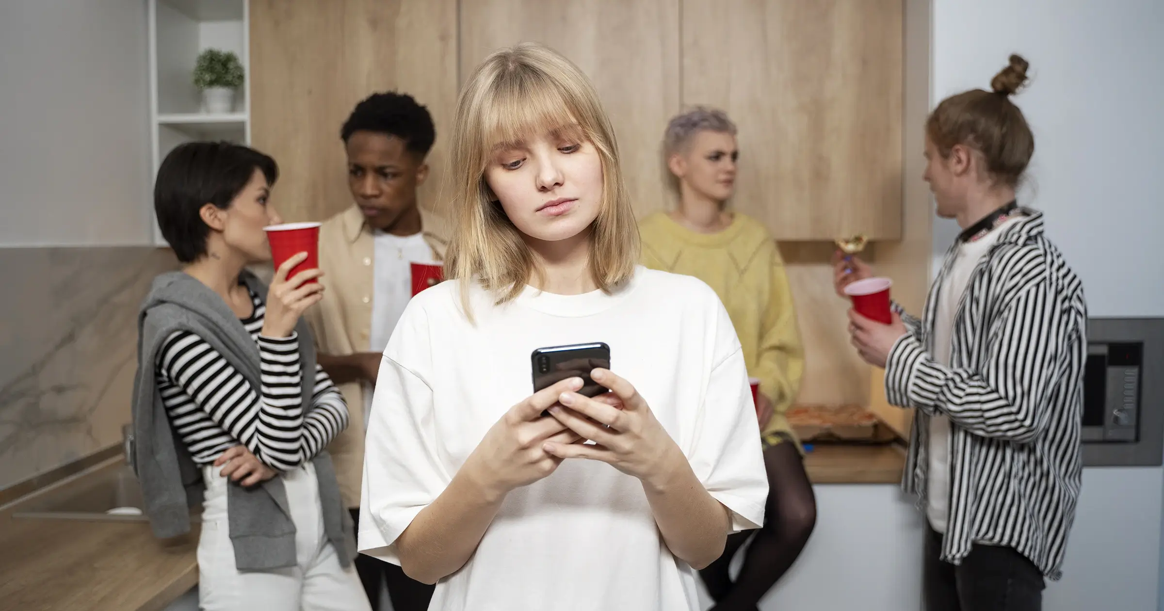 Woman alone and looking at her phone at a party