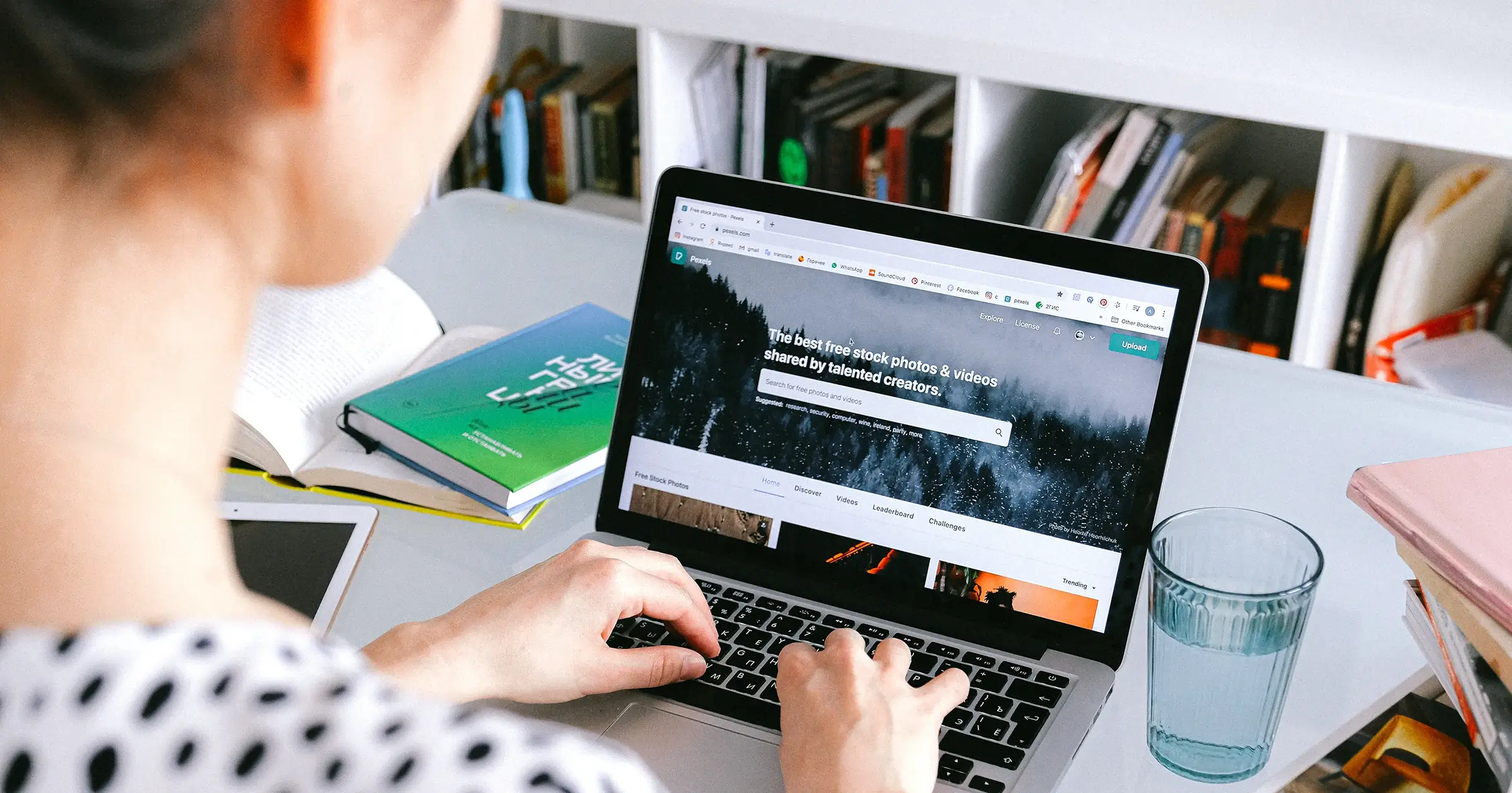 Woman using laptop with books in the background