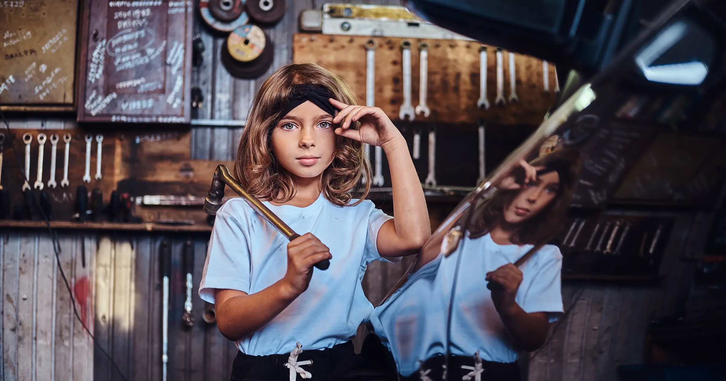 Young kid holding tools in a garage