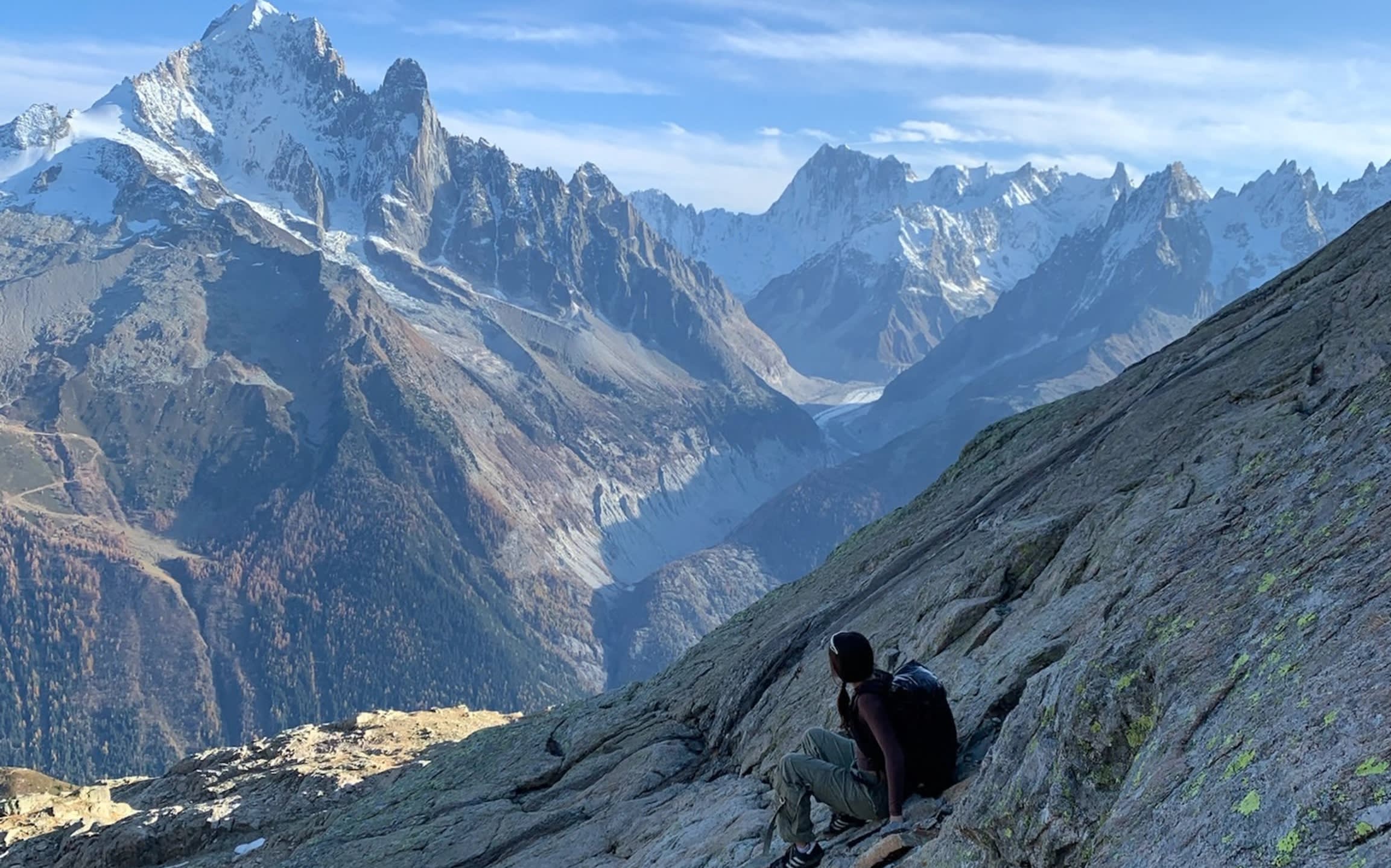 Traveler sitting on a granite slope overlooking alpine mountains