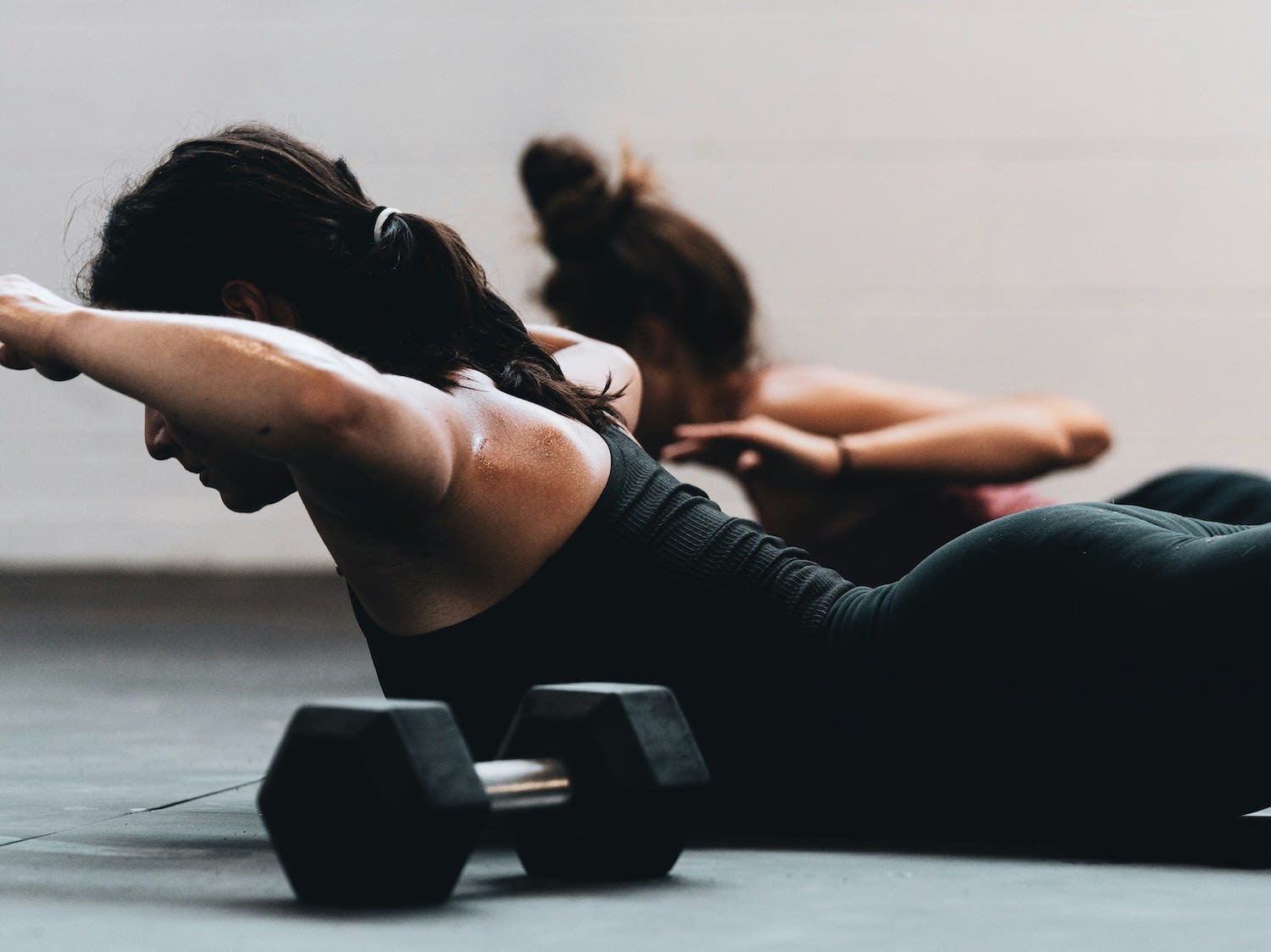 Runner performing a bodyweight strength exercise on the floor with a dumbbell for added resistance