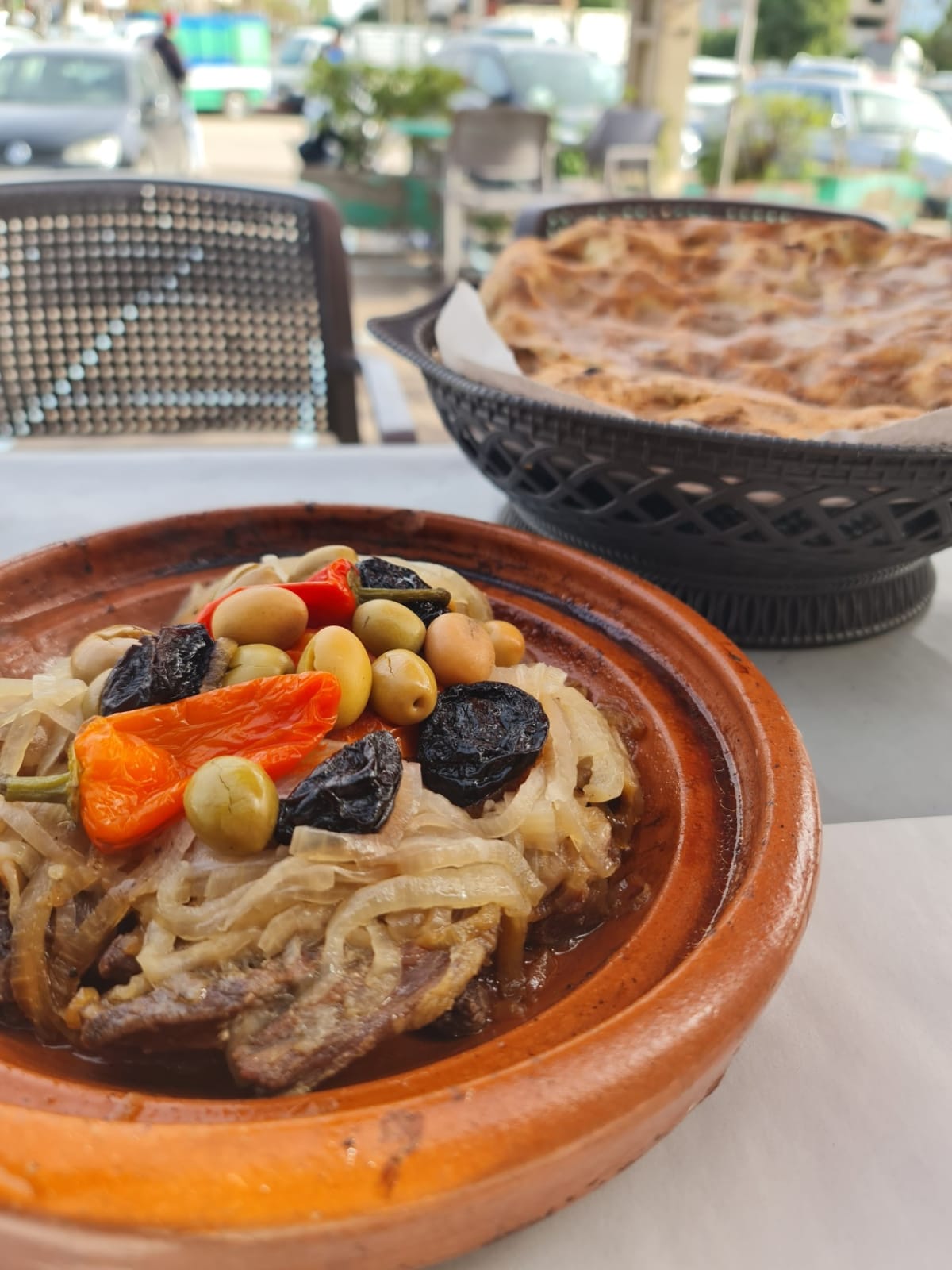 Tajine marocain aux olives et pruneaux confits, servi en terrasse