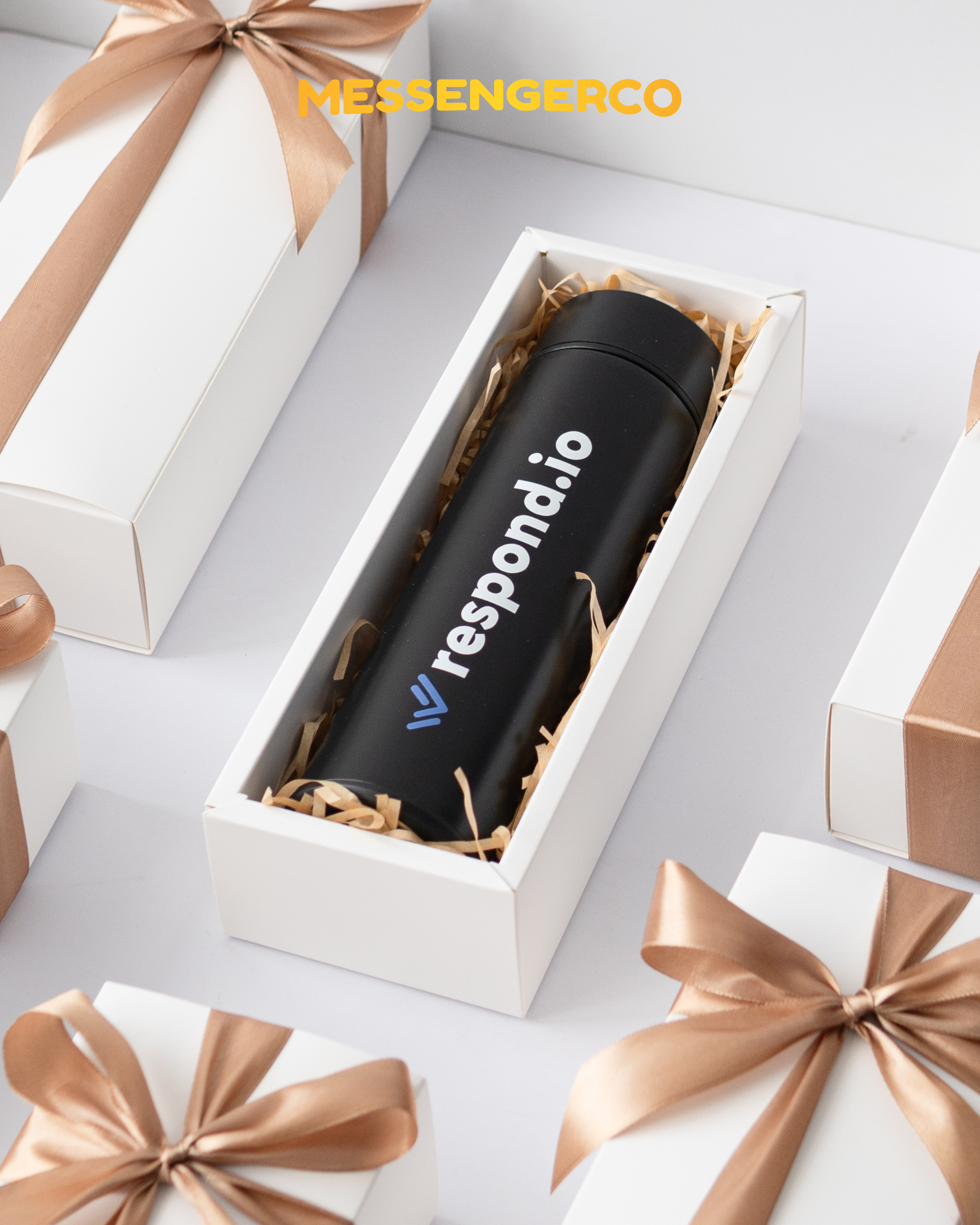 Rows of Messengerco Respond.io LED lid flasks in white boxes with shredded filler showing black bottles with printed logos.