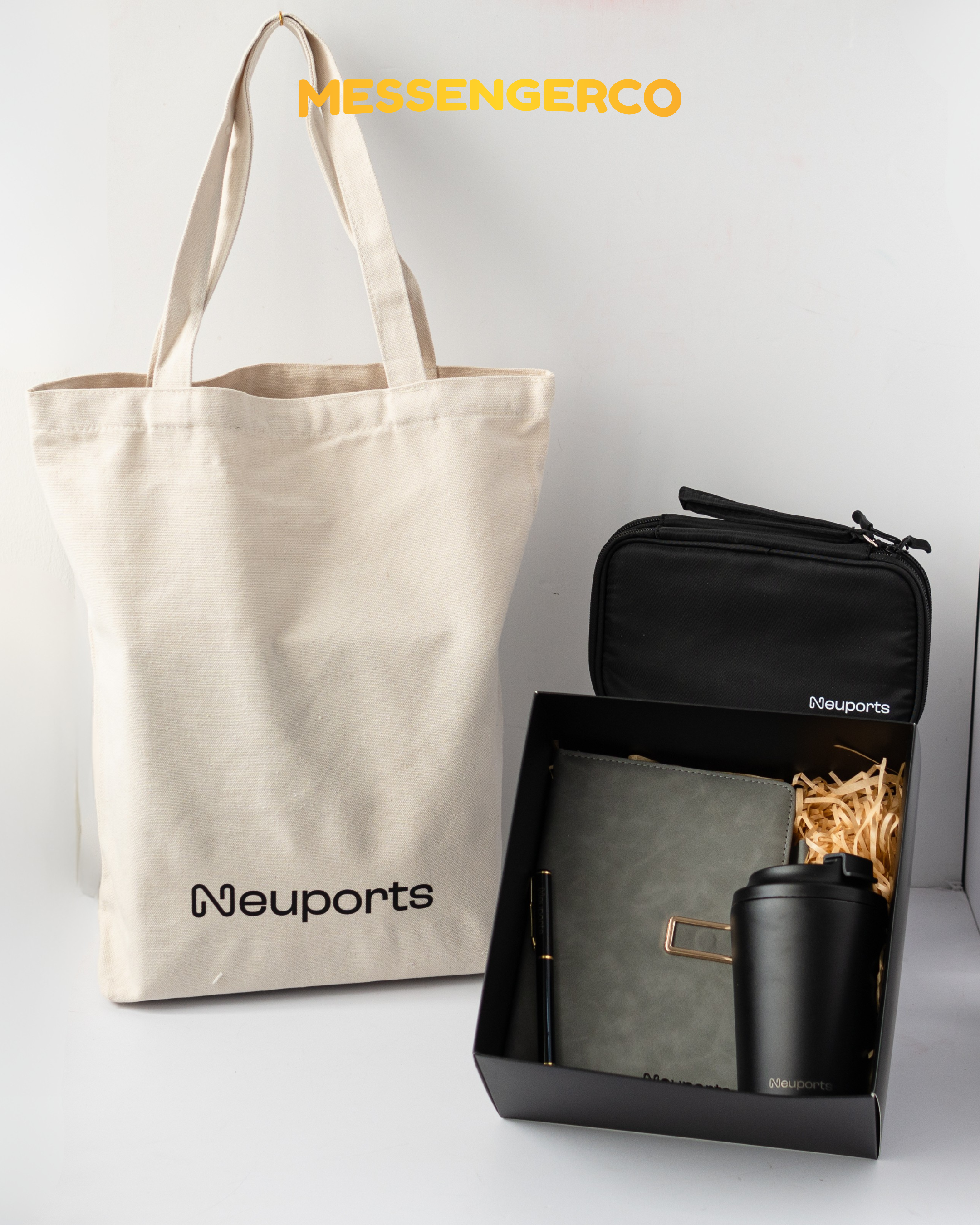 Open Messengerco welcome onboarding box for Neuports with grey notebook, pen, black tumbler and tech pouch beside beige tote.