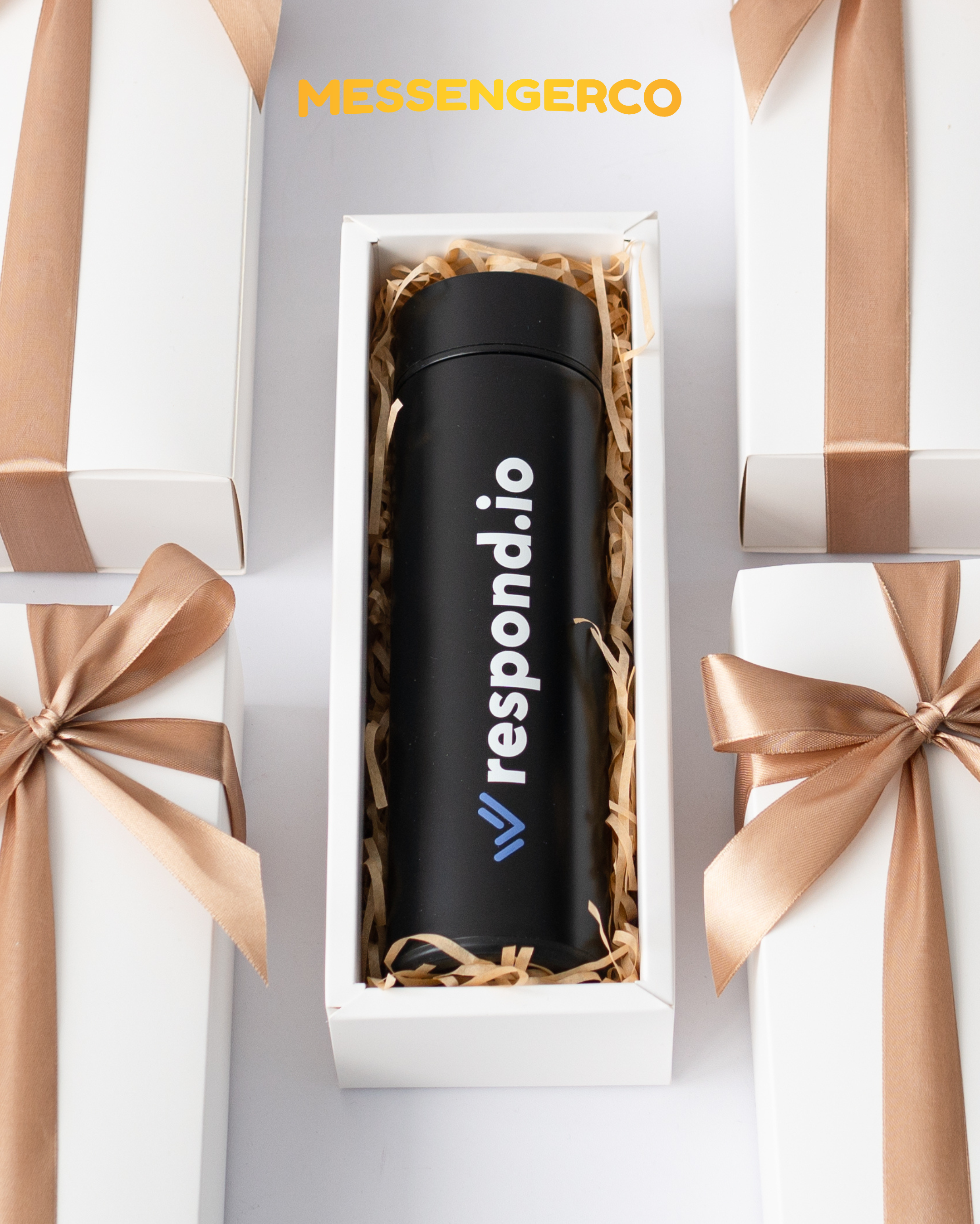 Messengerco Respond.io LED lid flask gift – black bottle in open white box with shredded paper among stacked ribboned boxes.