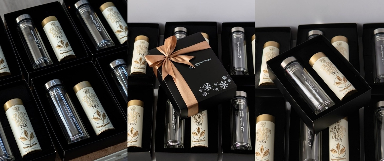 Premium christmas corporate gifts for Gleneagles Penang Hospital consists of black gift box with velvet foam, TWG tea, a double-layer glass bottle, a greeting card, shredded paper, satin ribbon, and a black paper bag.