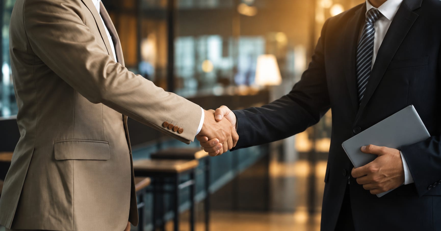 Business partners shaking hands in a warm corporate setting