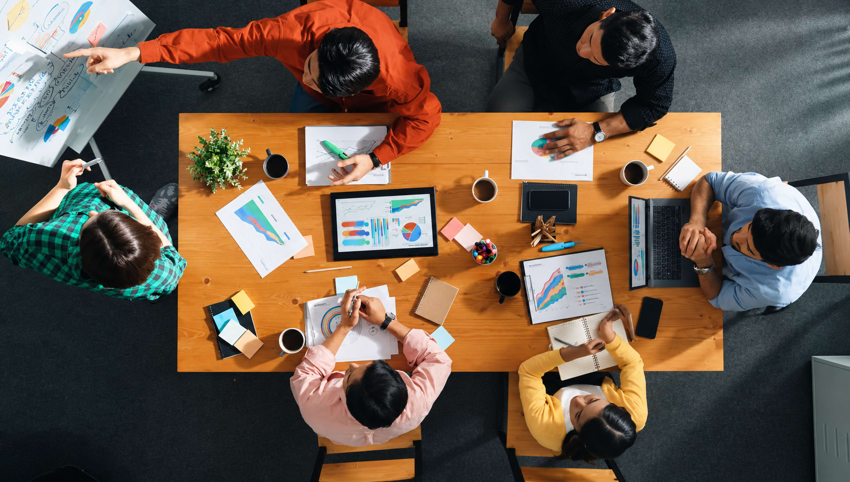 Team collaborating around a conference table with charts and sticky notes