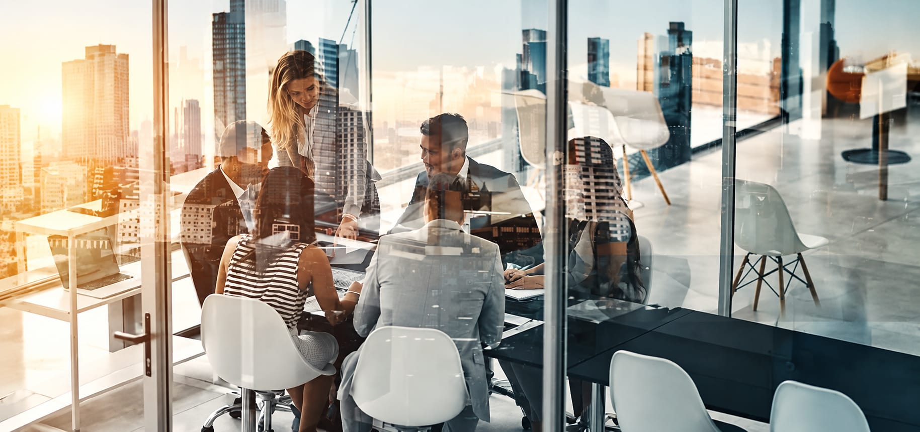 Team in a glass conference room overlaid with a sunlit city skyline
