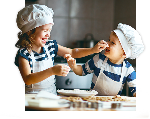 dwójka dzieci w fartuchach bawiąca się w kuchni