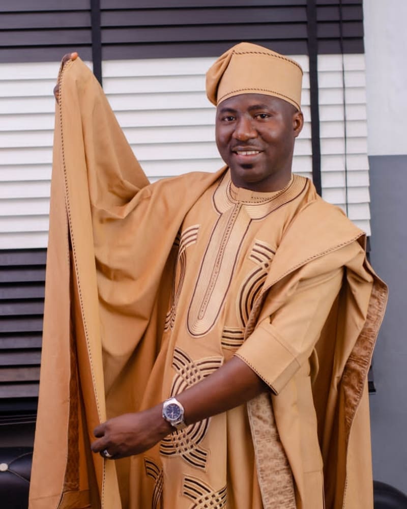 Man holding out the sleeve of his gold embroidered agbada