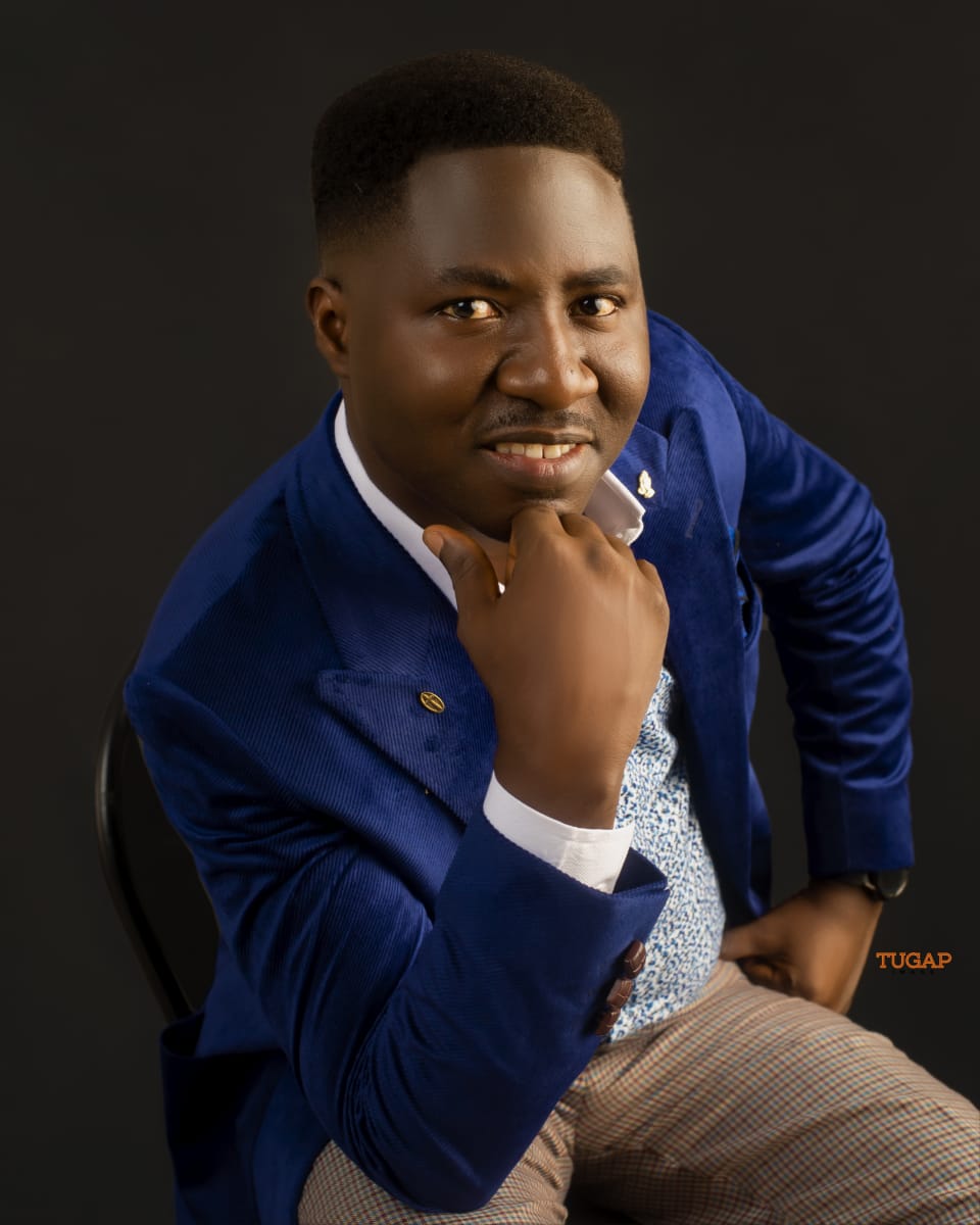 Close portrait of a man in a royal blue blazer resting his chin on his hand