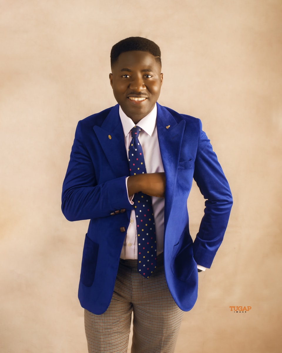 Smiling man in a royal blue blazer, dotted tie and check trousers