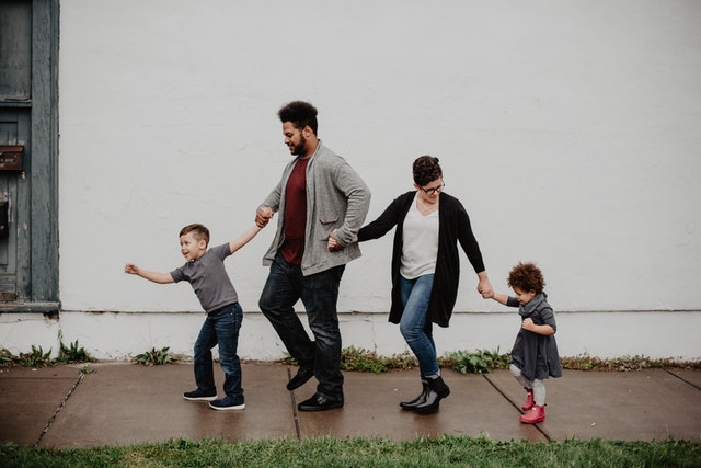 Parents holding hands with children on sidewalk