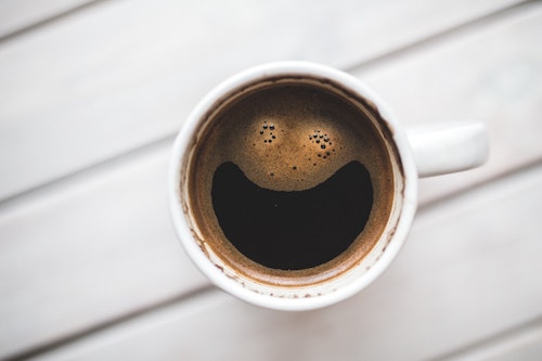 Coffee cup with a smiley face in the foam on top