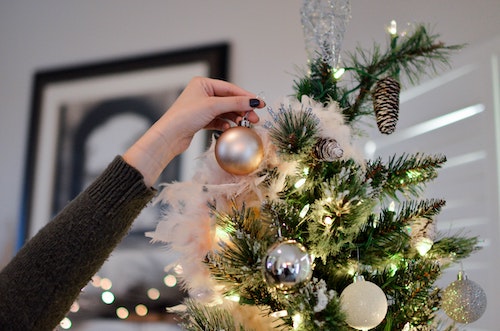 Person hanging ornaments on Christmas tree