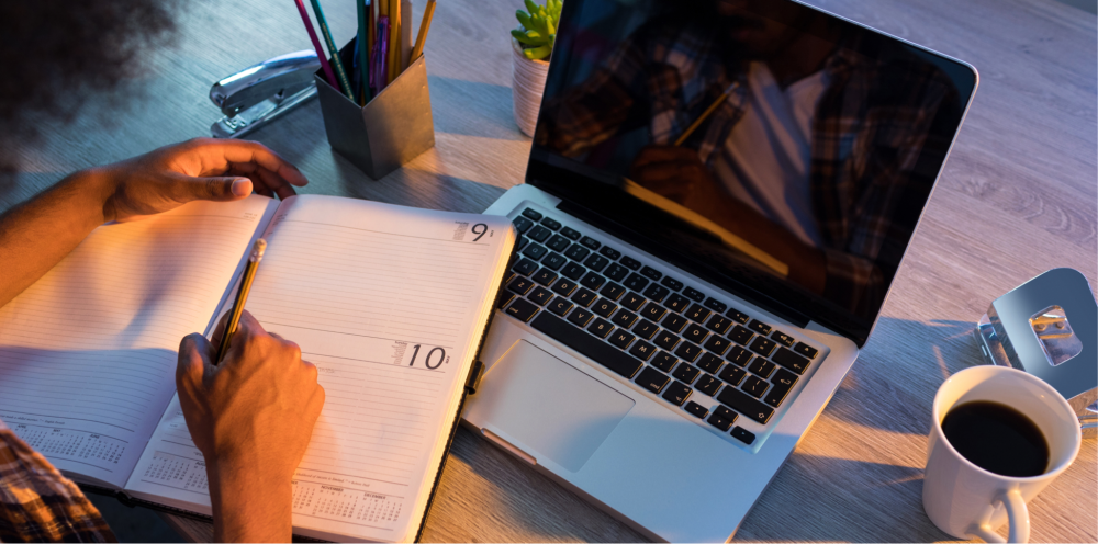 a desk with laptop and notebook