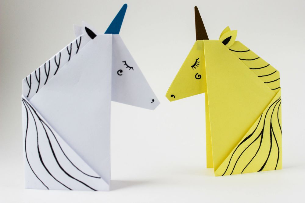 White and yellow unicorns made in the origami technique on white background