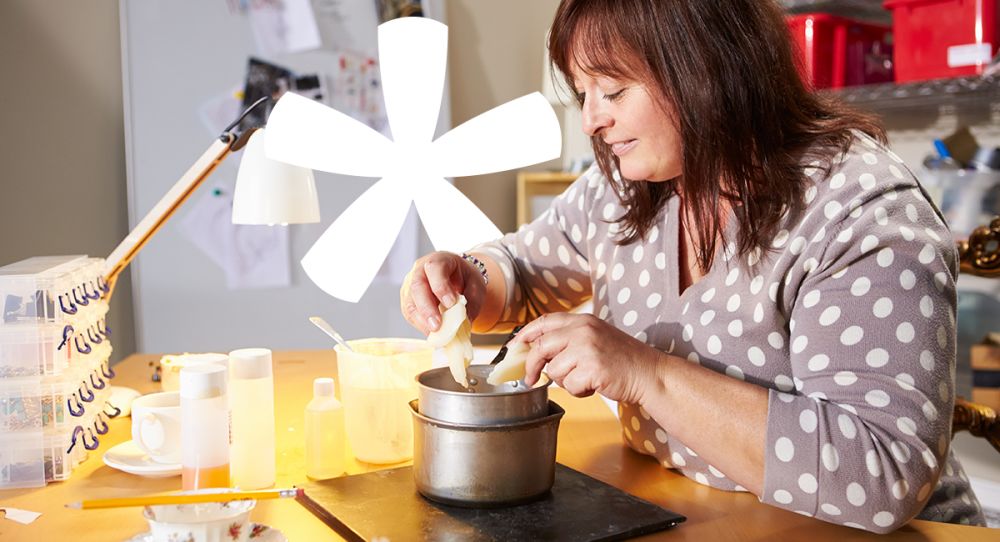 woman in a polka dot cardigan learning how to make a candle over a stove