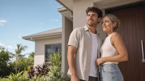 A couple standing at the front door of their new home in suburban Queensland, keys in hand