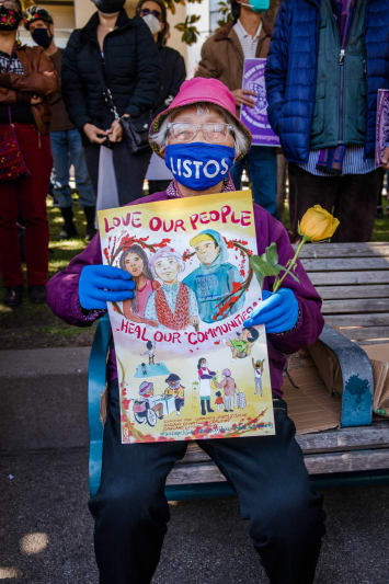 Frau sitzt auf Bank und hält Plakat als Protest gegen Hate speech