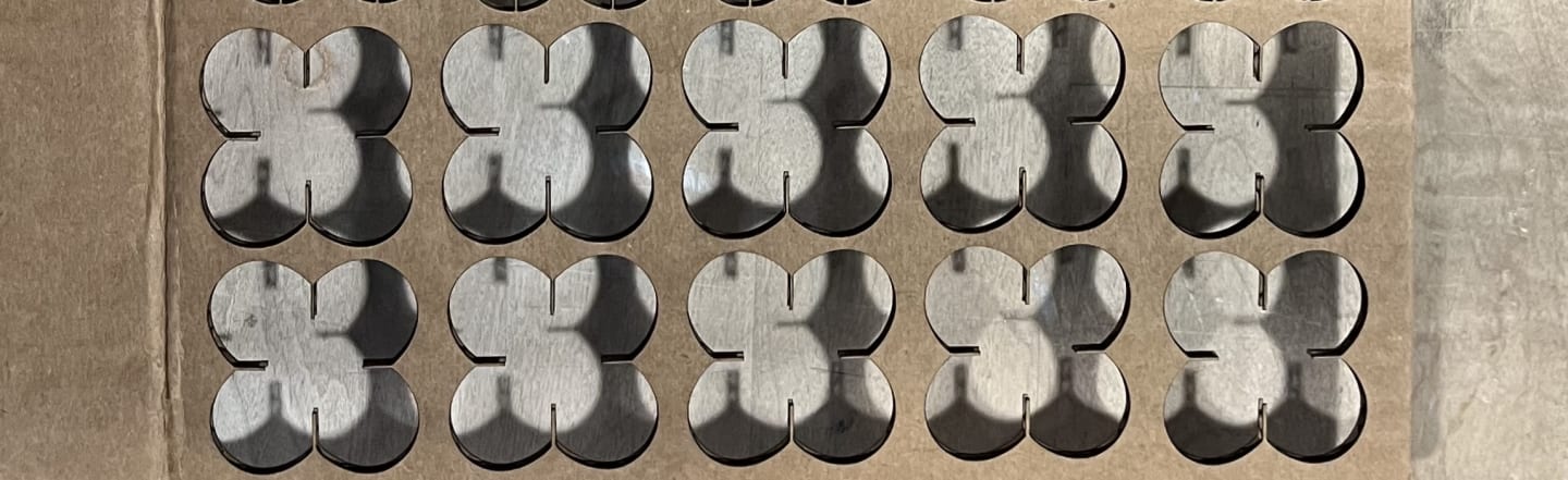 Photo of a laser cut out of cardboard, that has butterfly like repeated pattern.