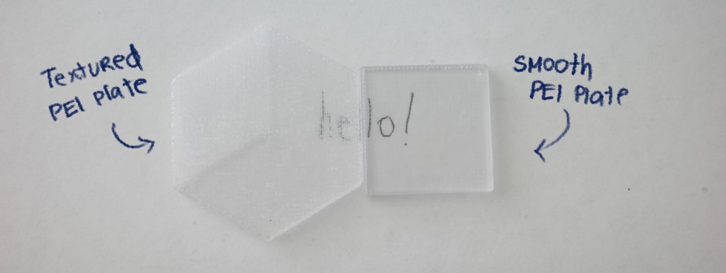 Photo comparing the textural differences between printing on a PEI plate and smooth PEI plate. 2 samples are placed next to each other to show the textured plate creating frost, and the smooth PEI plate looking clearer.