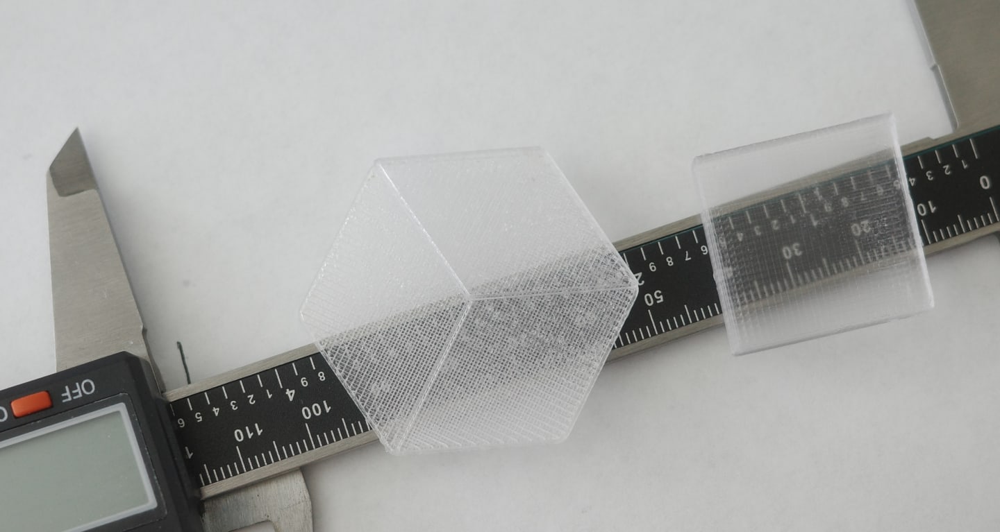 Photo of the two PETG samples printed with different plates on top of a caliper, to demonstrate transluceny differences betweent the two.