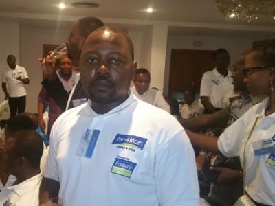 Des membres du personnel devant les panneaux de la nouvelle identité Pan-African Savings & Loans