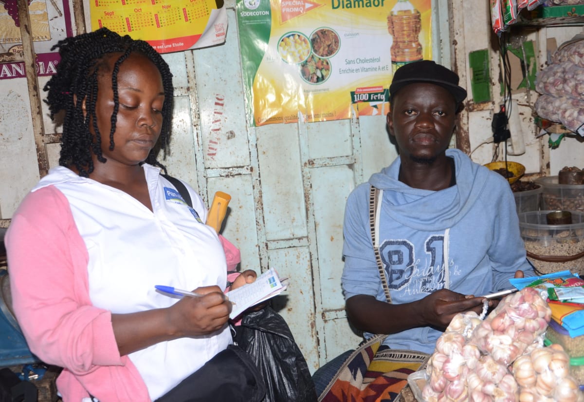 Une visite de terrain sur un étal de marché, prise de notes sur un carnet