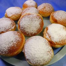 Faschingskrapfen mit Staubzucker bestreuen