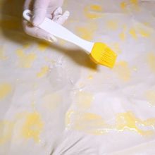Gezogenen Strudelteig mit Butter bestreichen