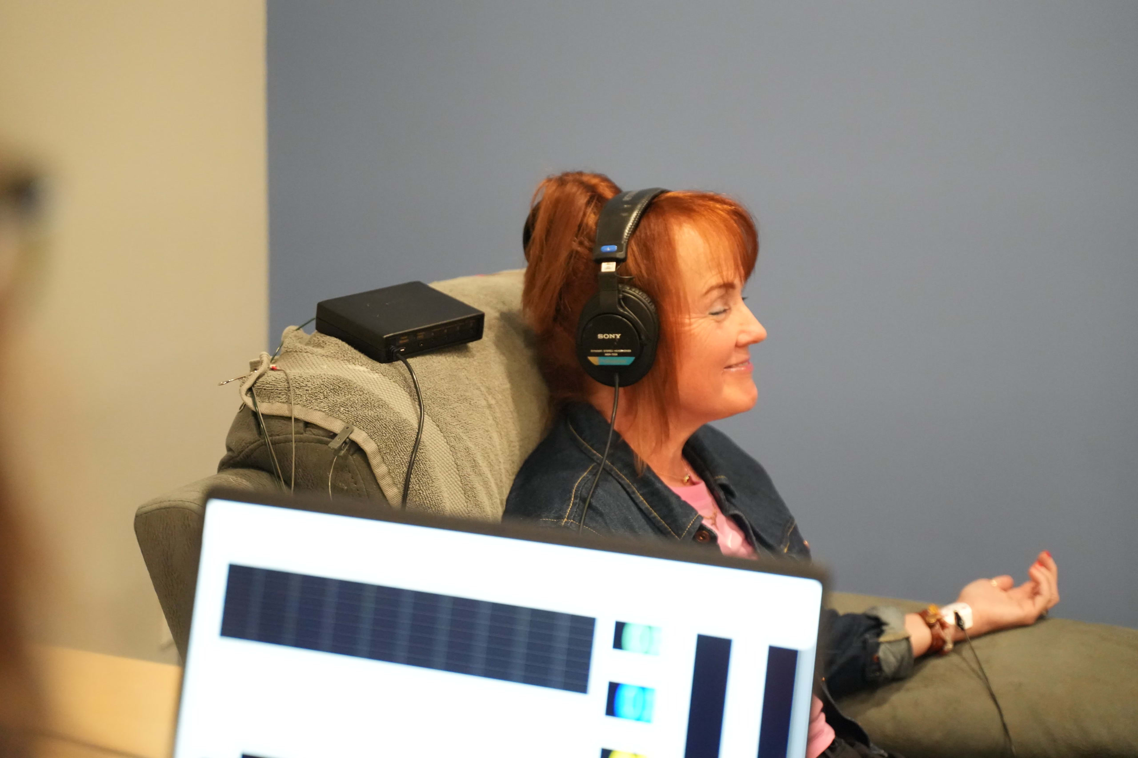 A participant seated wearing headphones with a software display screen in the foreground