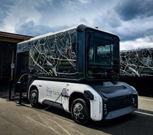 A futuristic-looking electric bus plugged in and charging.