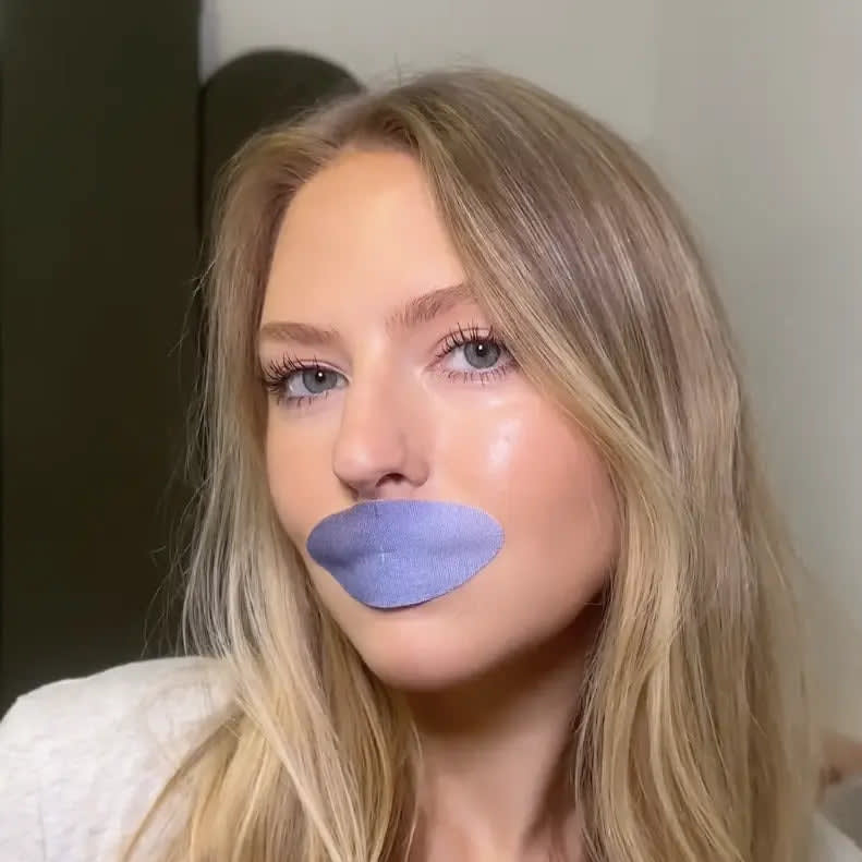 Woman wearing a purple lip mask while looking at the camera.