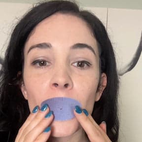 A person placing a blue circular pad over their mouth.
