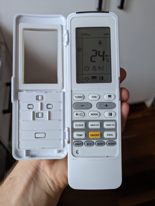 air conditioning remote with the flap open to reveal lots of buttons