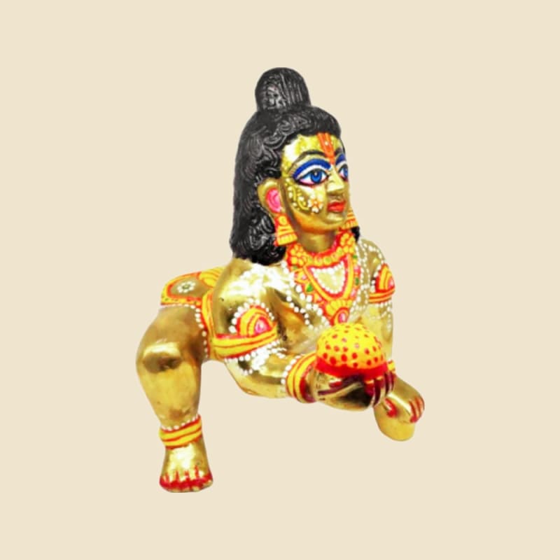 Brass Laddu Gopal, Crawling, Painted Black Hair and Face, Holding Laddoo on a warm ivory background