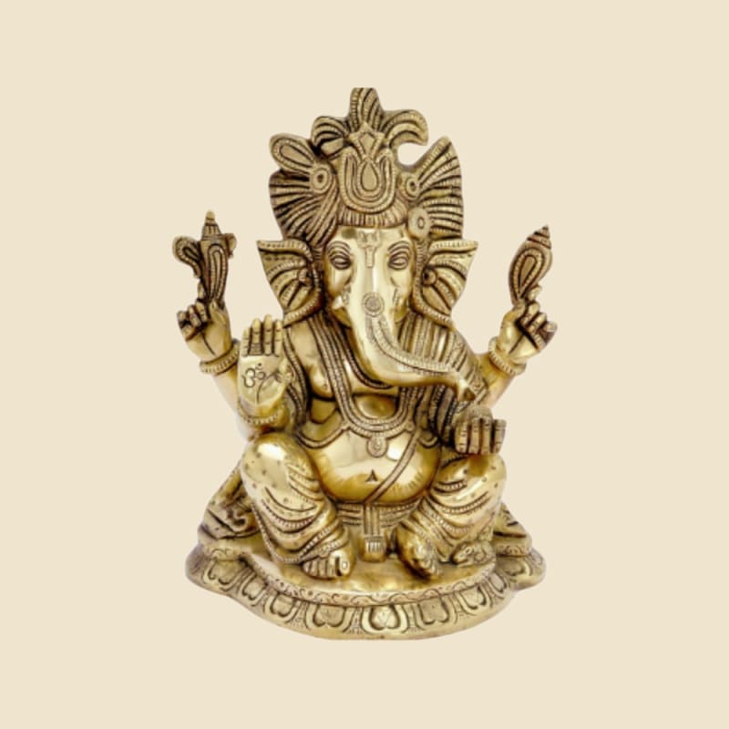 Brass Ganesha Seated, Ornate Crown, Antique Finish on a warm ivory background