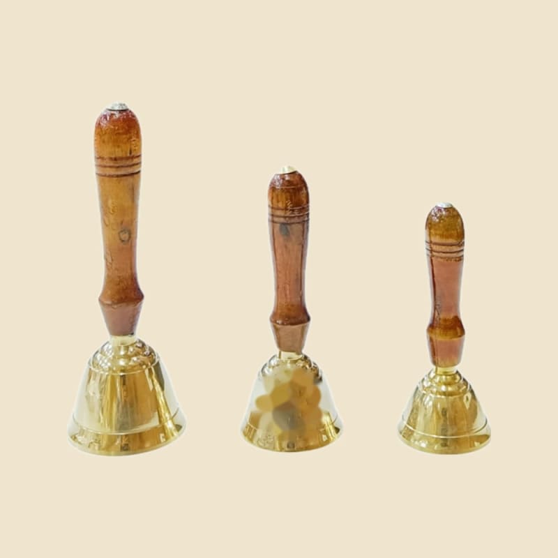 Brass Ghanti with Wooden Handle on a warm ivory background