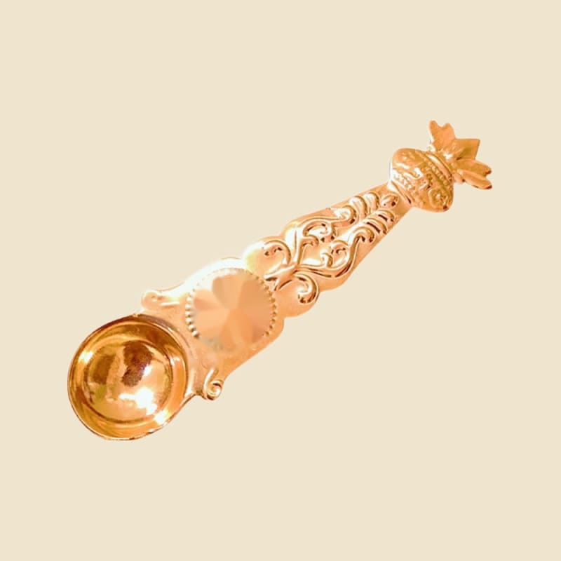 Copper Nariyal Sheet Palli (spoon) on a warm ivory background
