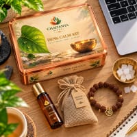 Close-up of roll-on, vetiver sachet, rudraksha mala and kapoor tablets in a brass bowl