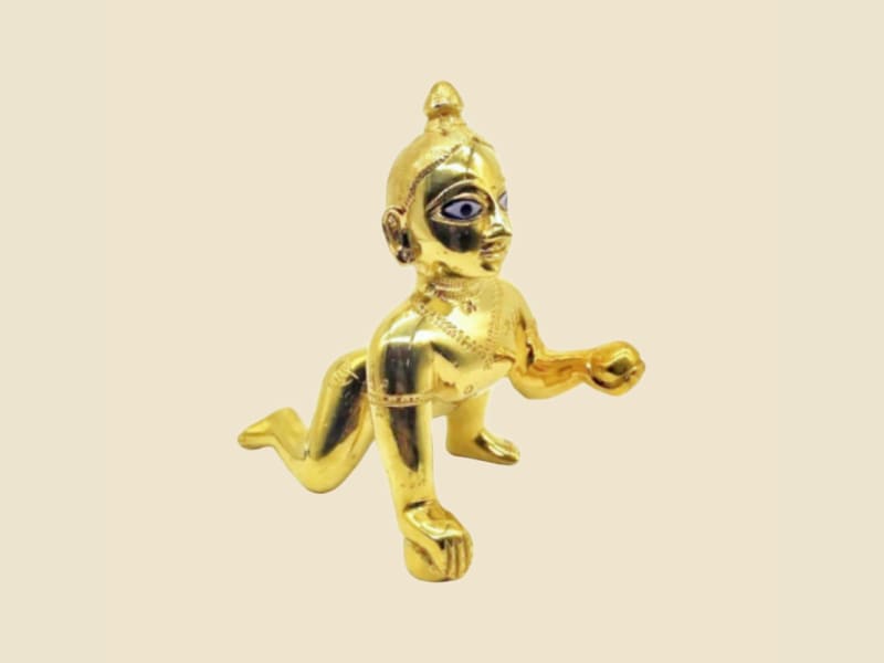 Polished Brass Laddu Gopal with Painted Eyes on a warm ivory background