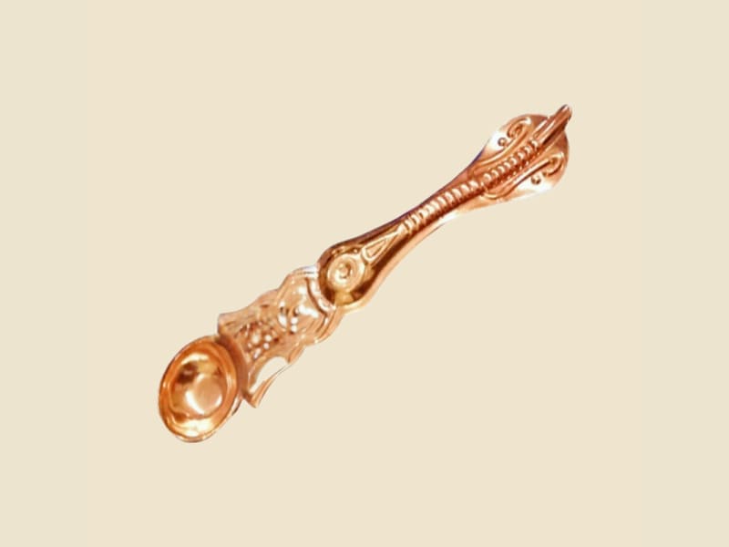 Copper Nakshi Palli (spoon) on a warm ivory background