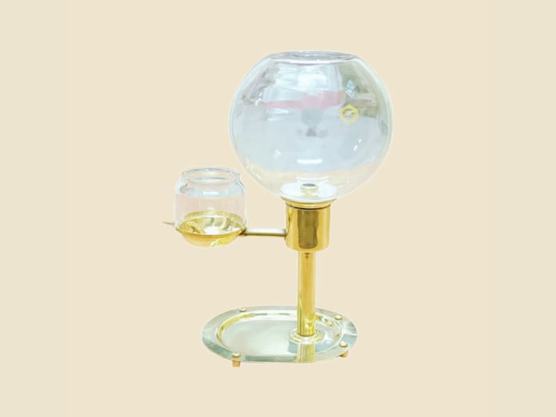Brass Oil Lamp Diya with Glass Globe on a warm ivory background