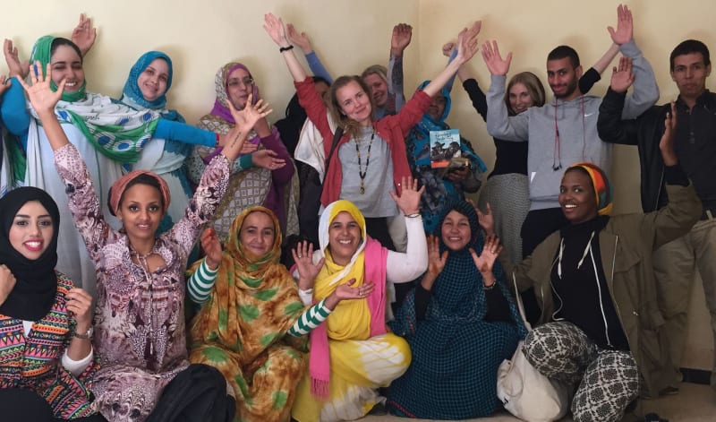 Group image of people all raising their hands cheering and looking happy 