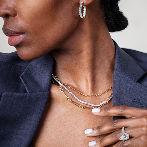 Model wearing assortment of gold and diamond necklaces and pendants